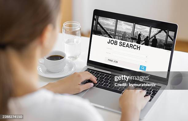 professional woman browsing online job search website on laptop at home - job search stock pictures, royalty-free photos & images