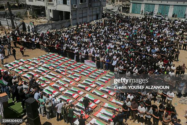 Mourners stand in rows to pray in front of wrapped bodies amid destroyed buildings during a mass funeral in Gaza City, Gaza Strip, on August 4, 2026....