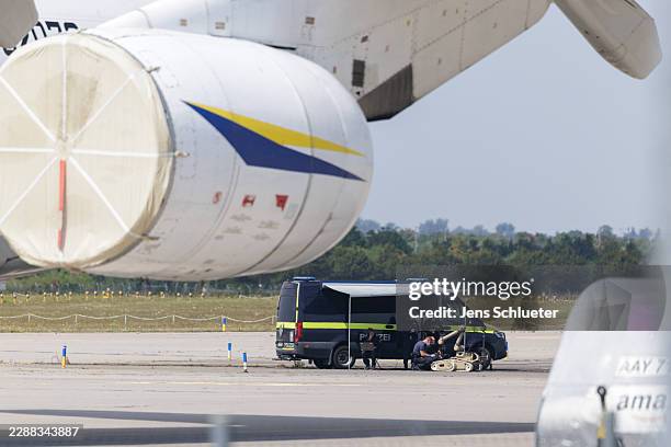 Police investigators work on the tarmac with a robot that is capable, amongst other things, of defusing explosives, near to Ukrainian Antonov cargo...