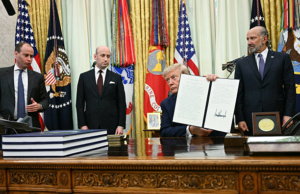 President Donald Trump holds up a newly signed executive order on adjusting imports of polysilicon in the Oval Office of the White House in...