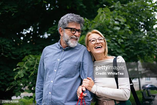 smiling senior couple walking arm in arm outdoors - pair stock pictures, royalty-free photos & images