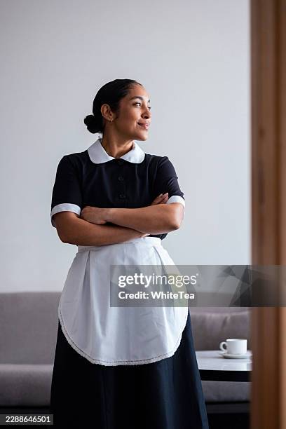 gouvernante confiante en uniforme, debout, bras croisés - chambre bien rangée photos et images de collection