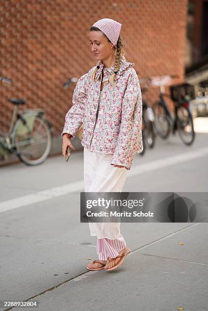Guest is seen wearing a floral quilted jacket with a ruffled collar; a white textured midi dress layered over pink striped wide leg trousers; pale...