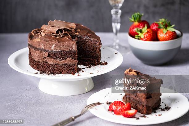 chocolate cake placed on a cake stand with strawberries and drink in the background. - chocolate cake stock pictures, royalty-free photos & images