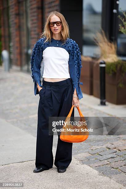 Laura Schulte is seen wearing a navy and white long sleeve cropped top with textured floral appliqué sleeves from Arisholm; navy wide leg tailored...