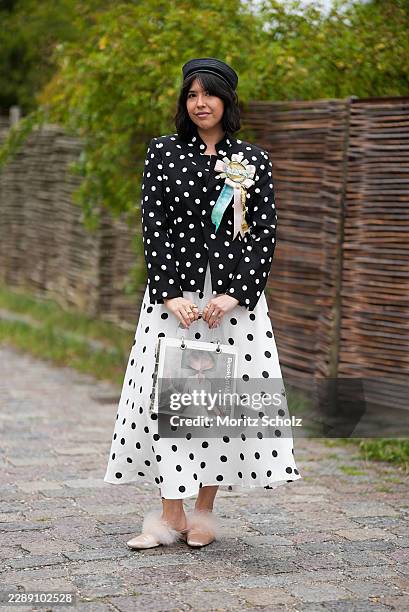 Guest is seen wearing a black and white polka dot blazer layered over a matching polka dot midi dress, a black pillbox hat, feather trimmed flats and...