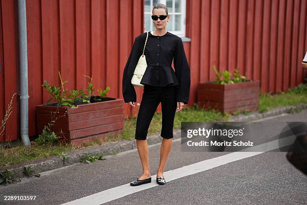 Vera van Erp is seen wearing a structured black peplum jacket, black cropped trousers, black cat eye sunglasses, Chanel ballerinas and carrying a...