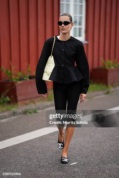 Vera van Erp is seen wearing a structured black peplum jacket, black cropped trousers, black cat eye sunglasses, Chanel ballerinas and carrying a...