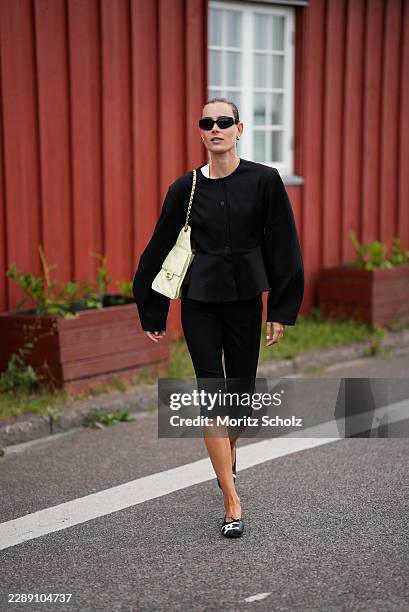 Vera van Erp is seen wearing a structured black peplum jacket, black cropped trousers, black cat eye sunglasses, Chanel ballerinas and carrying a...