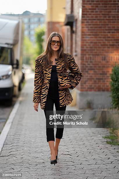 Nina Sandbech is seen wearing a tiger print blazer, a black top, black cropped trousers, oversized sunglasses, black pointed toe pumps and carrying a...