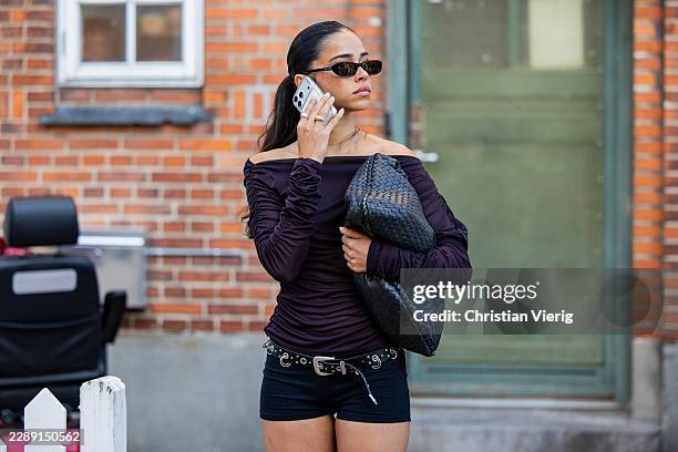 Guest wears off shoulder purple long sleeved top, black bag, shorts outside Gestuz during the Copenhagen Fashion Week Spring/Summer 2027 on August...