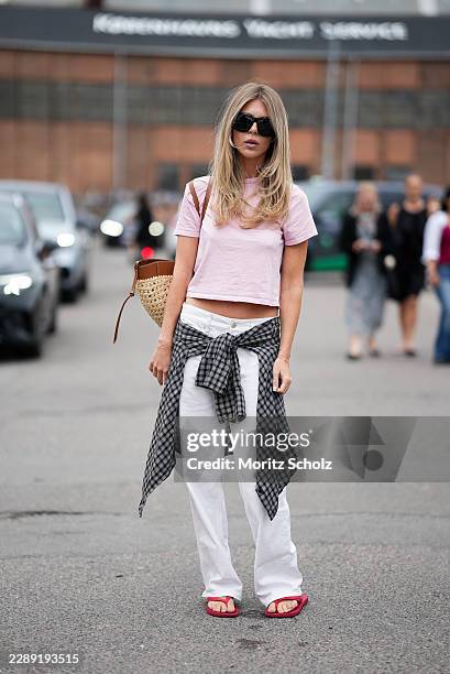 Guest is seen wearing a light pink cotton short sleeve cropped T shirt; a black and grey checked shirt tied around the waist; white wide leg...