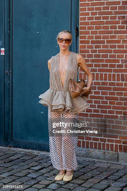 Josefien Weyns wears cut out sleeveless ruffled dress, transparent white skirt, brown bag, sunglasses outside Herskind during the Copenhagen Fashion...