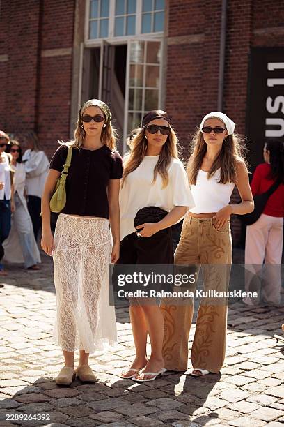 Guest wears dark brown T-shirt, white lace skirt, green bag, sunglasses and a head scarf and a guest wears black skirt, white top, sunglasses and...