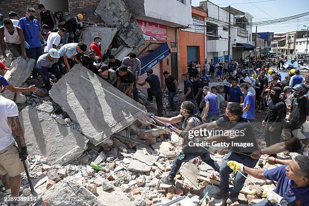People and rescuers search for victims amid debris of a collapsed building at La Alameda neighborhood after a magnitude 7.4 earthquake struck...