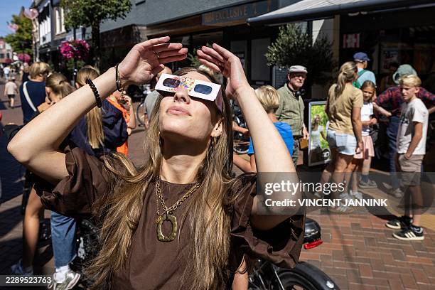 Woman wears eclipse glasses in Almelo, eastern Netherlands on August 11, 2026 on the eve of a partial solar eclipse. The scramble for protective...