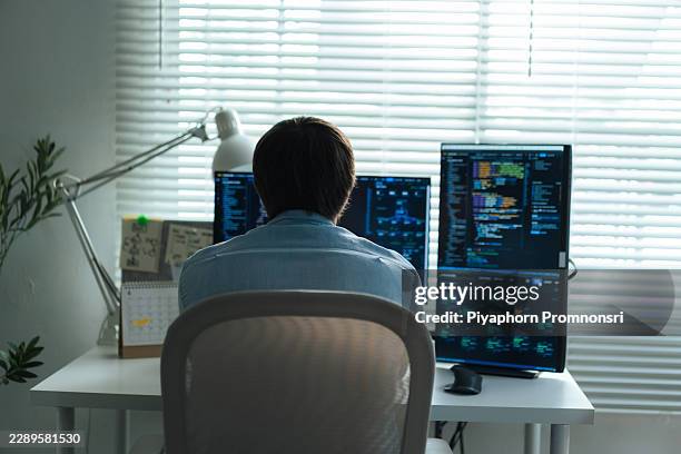 male computer programmer working at office workstation with multiple screens showing code and data, focused on software development, debugging, computer network, data science and network security. - network admin stock pictures, royalty-free photos & images