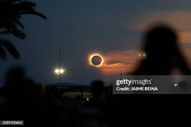 The Sun's corona glows as the Moon completely blocks the Sun during the totality phase of the total solar eclipse as seen from Arenal beach in...