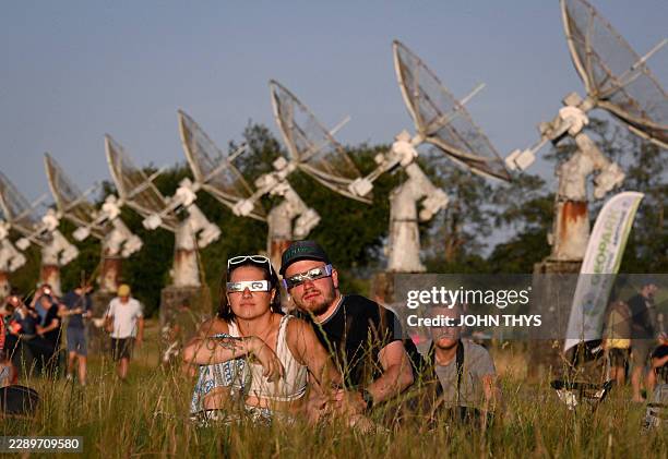 Attendees watch using solar eclipse viewing glasses as the moon fully passes over the sun's horizon during a partial solar eclipse at the Royal...