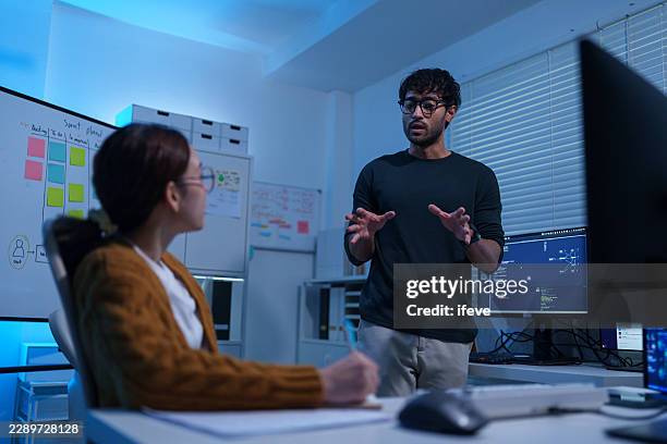 indian male programmer discussing software project with chinese female developer - java programmer stock pictures, royalty-free photos & images