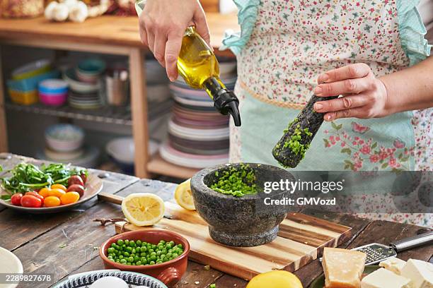 preparare il pesto di piselli freschi in cucina - mortaio con pestello foto e immagini stock