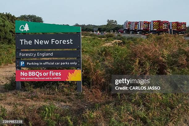 Fire engines are pictured behind a sign for the New Forest notifying visitors not to have BBQs or light fires, as wildfires have burned in the area...