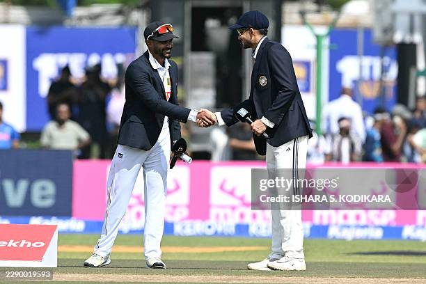 Sri Lanka's captain Dhananjaya de Silva shakes hands with India's captain Shubman Gill during the toss on the first day of the first Test cricket...