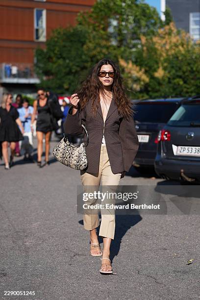 Guest wears long wavy brown hair with a center part, brown rectangular sunglasses with tinted lenses, a brown check oversized blazer jacket with a...