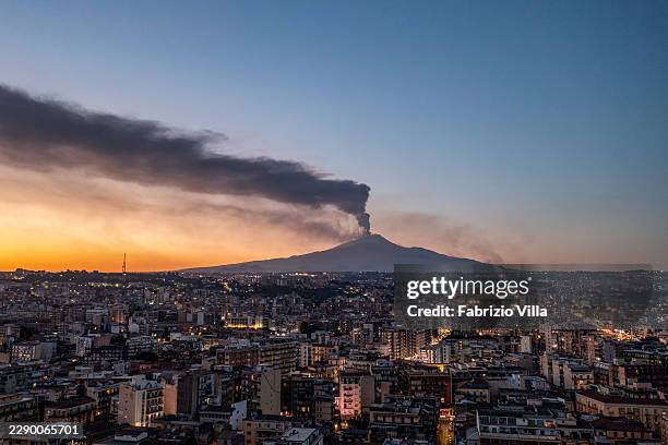 An aerial view of the city of Catania at sunset, with Mount Etna emitting a large plume of volcanic ash in the background, on August 11, 2026 in...