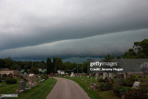 Person walks through Rose Hill Cemetery as a shelf cloud approaches behind them ahead of a severe thunderstorm on August 11 in Bloomington, Indiana....