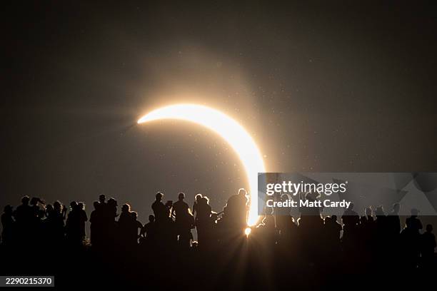 People view the partial solar eclipse besides the historic St. Michael's Church tower, a Grade I listed building at the top of Glastonbury Tor on...