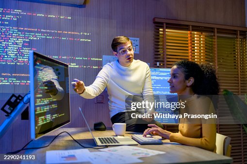 Software developers collaborating on an artificial intelligence project, analyzing code on multiple computer screens in a modern tech office environment at night Software developers collaborating on an artificial intelligence project, analyzing code on multiple computer screens in a modern tech office environment at night