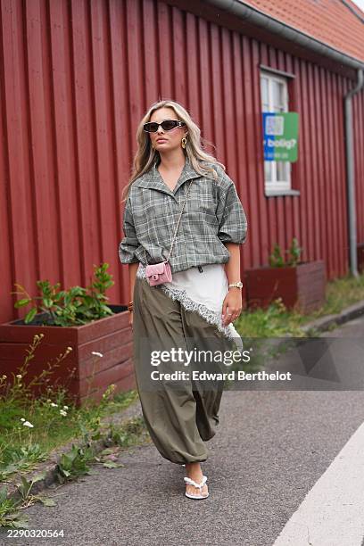 Guest wears long wavy blonde hair with a center part, black cat-eye sunglasses with dark lenses by Chanel, a gray plaid checkered rolled up...