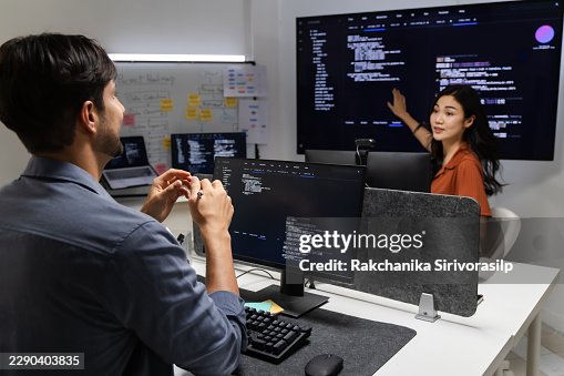 Software development team discussing source code on large office monitors, collaborating on debugging, system analysis, and programming decisions to improve application reliability. Software development team discussing source code on large office monitors, collaborating on debugging, system analysis, and programming decisions to improve application reliability.