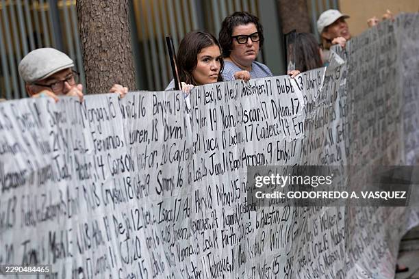 Family members and supporters hold a banner with the names of nearly 400 young people who allegedly died from the impacts of social media outside the...