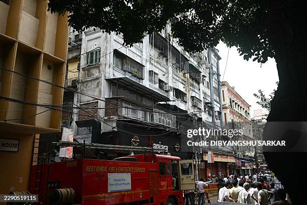 Onlookers and fire personnel gather at the site following a fire at a hotel in Kolkata on August 19, 2026. At least nine people were killed and...