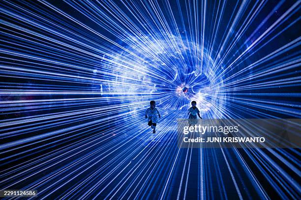 Children run at the recently opened Space and Time Cube Surabaya immersive digital art space, in Surabaya on August 23, 2026. / RESTRICTED TO...