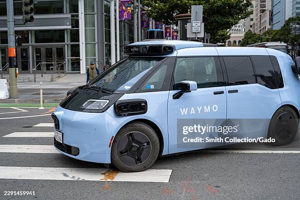 Waymo Ojai electric autonomous ride-hailing vehicle crosses Fourth Street outside Moscone West in the South of Market district, San Francisco,...