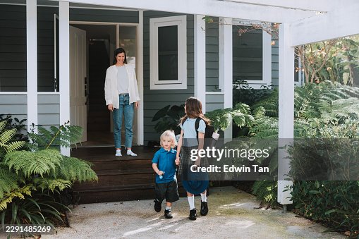 I bambini bianchi camminano verso la scuola mentre la madre osserva I bambini bianchi camminano verso la scuola mentre la madre osserva