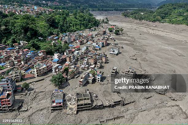 Houses lie partially submerged in muddy water along a riverside after flash floods at Trishuli Bazar in Nepal's Nuwakot district on August 26, 2026....