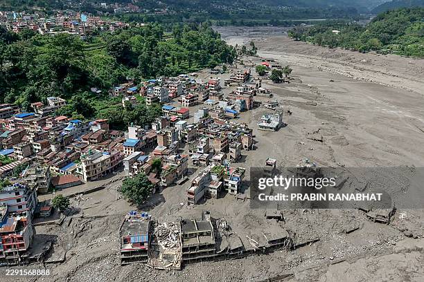 This aerial view shows houses laying partially submerged in muddy water along a riverside after flash floods at Trishuli Bazar in Nepal's Nuwakot...