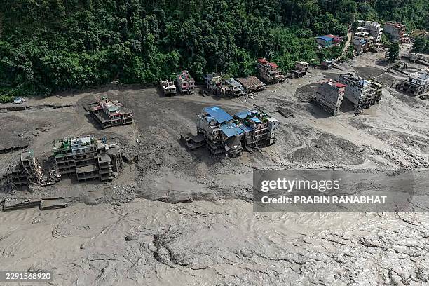 This aerial view shows houses laying partially submerged in muddy water along a riverside after flash floods at Trishuli Bazar in Nepal's Nuwakot...