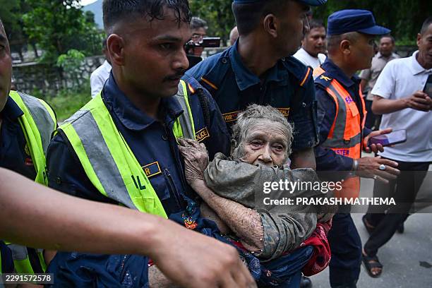 Rescue personnel carry a person affected by flash floods at Devghat in Nepal's Nuwakot district on August 26, 2026. Massive flooding killed eight...