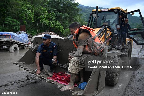 Rescue personnel use an excavator to carry a person affected by flash floods at Devghat in Nepal's Nuwakot district on August 26, 2026. Massive...