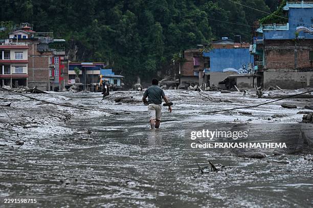 Resident walks along a street covered in mud following flash floods and a landslide disaster in Devighat, in Nepal's Nuwakot district on August 26,...