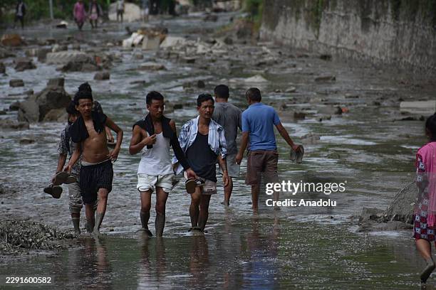 People walk along a road covered by floodwaters in Nuwakot, Nepal, on August 26, 2026. The powerful flood, originating from the Tibet region of...