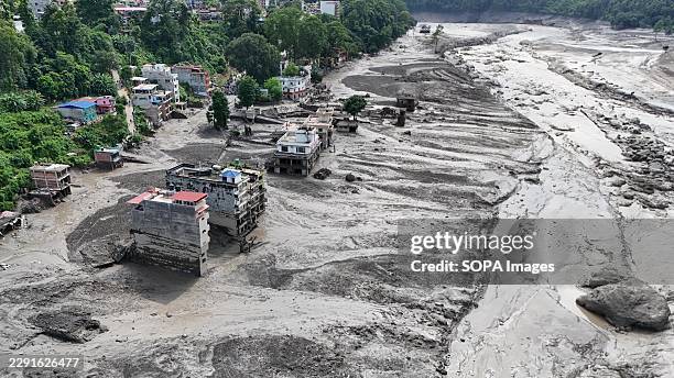 An aerial view shows buildings and infrastructure damaged along the swollen Trishuli River following a massive flash flood triggered by an avalanche...