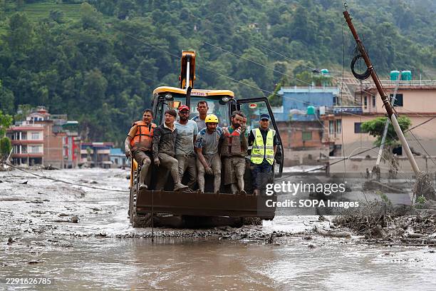 Security personnel rescue people in a bulldozer from buildings that were damaged along the swollen Trishuli River following a massive flash flood...