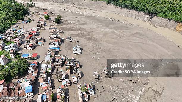 An aerial view shows buildings and infrastructure damaged along the swollen Trishuli River following a massive flash flood triggered by an avalanche...