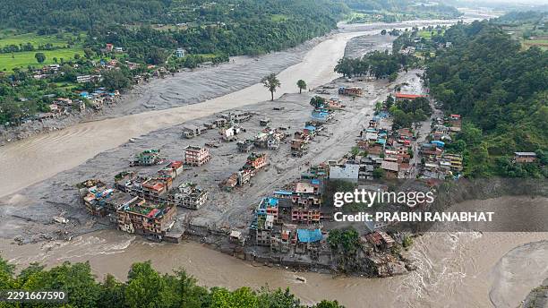 An aerial view shows houses lying deluged in sludge after flash floods at Devighat, Bidur Municipality in Nepal's Nuwakot district on August 27,...